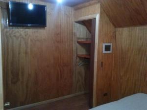 1 dormitorio con TV en una pared de madera en Hostal Lagunitas en Puerto Montt