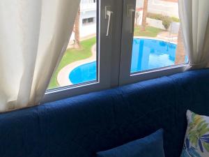 Sofá azul frente a una ventana con vistas a la piscina en Complejo Andalucía Torrecilla Beach, en Nerja