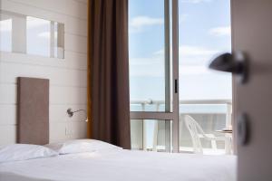 a bedroom with a bed and a view of a balcony at Hotel Majestic in Milano Marittima