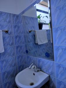 Baño de azulejos azules con lavabo y espejo en FLOZZY HOMES, en Kisumu