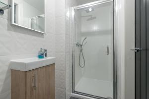 a white bathroom with a shower and a sink at Pass The Keys Main Door 3 Bed Apartment with Free Parking in Edinburgh