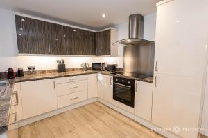 a kitchen with white appliances and wooden cabinets at Elegant townhouse, Westbourne, Sleeps 8, Parking - The Hideaway in Bournemouth