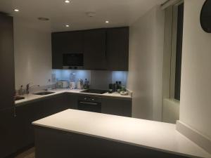 a kitchen with black cabinets and a white counter top at GRAND SERVICED APARTMENT***** in Croydon