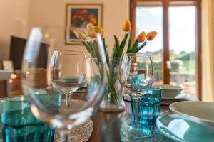 a table with wine glasses and a vase of flowers at Casa Elsa - Lago d'Orta in Orta San Giulio