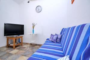 sala de estar con sofá de rayas azules y TV en Apartment Bujas, en Šilo