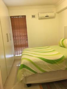 a bedroom with a bed with a green and white blanket at Ballito Sands in Ballito