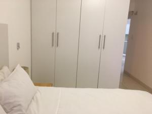 a bedroom with white cabinets and a white bed at Ballito Sands in Ballito