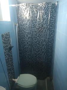 y baño azul con aseo y ducha. en Quarto em Caraguatatuba litoral norte, en Caraguatatuba