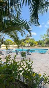里約熱內盧的住宿－Apartamento Barra Villa d Italia HIR 32，享有带椅子和棕榈树的游泳池的景色
