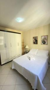 un dormitorio con una cama blanca con un perro sobre ella en Apartamento Barra Villa d Italia HIR 32, en Río de Janeiro