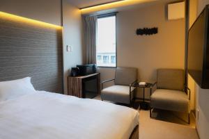 Habitación de hotel con 1 cama y 2 sillas en ピンポンホテル&キャビン pin pon hotel & cabin, en Shunan