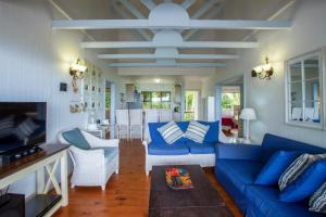 a living room with a blue couch and white chairs at Campismo Ninho 29 in Ponta Malongane
