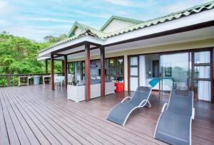 une maison avec deux chaises sur une terrasse en bois dans l'établissement Campismo Ninho 29, à Ponta Malangane