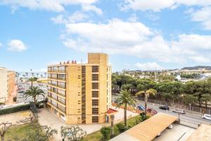 a tall yellow building with palm trees and a city at HOMES & GO TURQUESA in La Pineda