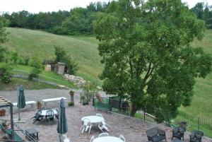 un patio con mesas, sillas y un árbol en Agriturismo Petrarosa en Neviano degli Arduini