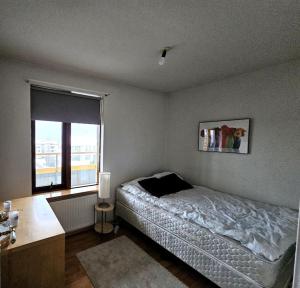 um quarto com uma cama, uma secretária e uma janela em Family penthouse with great view em Garðabær