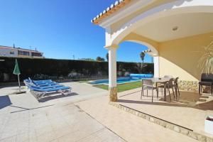 un patio con tavolo e sedie e una piscina di Bonita Moradia c/ Piscina em SAGRES a Sagres