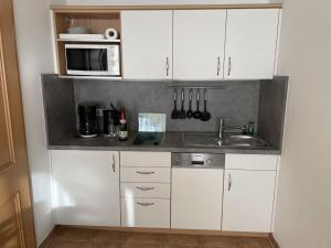 オストゼーバート・ゼリンにあるApartment Stolzenfels-3 by Interhomeの白いキャビネット、シンク、電子レンジ付きのキッチンが備わります。