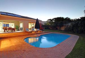 a swimming pool in a yard with a patio at Durham Close 31 by HostAgents in Bloubergstrand