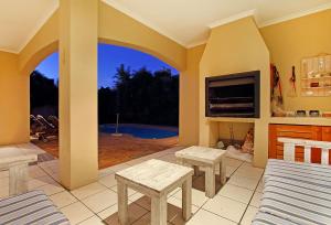 a patio with two benches and a table and a fireplace at Durham Close 31 by HostAgents in Bloubergstrand