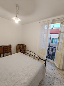 ein weißes Schlafzimmer mit einem Bett und einem Fenster in der Unterkunft La Scalinata in Bordighera