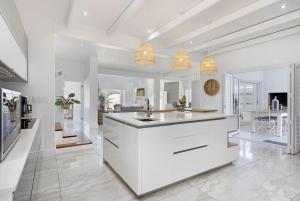 una cucina con armadi bianchi e piano di lavoro di Endless Summer Beach House a Bloubergstrand