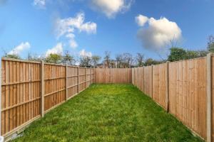une clôture en bois avec une cour avec de l'herbe verte dans l'établissement 3BR Retreat, Allocated Parking, Private Garden, à Windsor