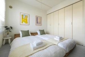 a white bedroom with a large bed with towels on it at Cozy Stay Sapporo East in Kita-sanjō