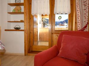 ein Wohnzimmer mit einem roten Stuhl und einem Fenster in der Unterkunft Apartment Deluca - PFS466 by Interhome in Pozza di Fassa