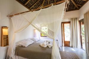 a bedroom with a canopy bed with two stuffed animals on it at Pousada Colmeia - Praia de Santo André, Bahia in Santo André