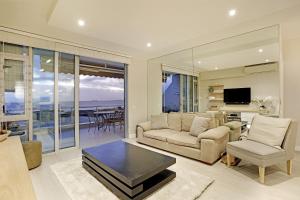 a living room with a couch and a table at Dolphin Beach H106 by HostAgents in Bloubergstrand
