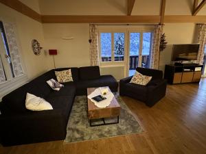 sala de estar con sofá negro y mesa en Holiday Home Chalet Ahornen by Interhome, en Grindelwald