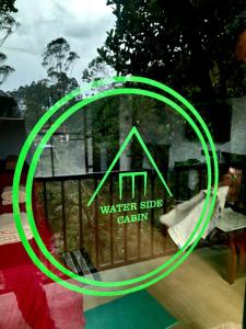 a green sign on a window with a water side cabin at Water Side Residence in Adams Peak