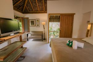 a room with a bed with a television and a couch at Pousada Colmeia - Praia de Santo André, Bahia in Santo André