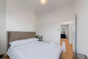 um quarto com uma grande cama branca com lençóis brancos em Stunning 1-bed Flat in London 20 mins from Central London em Londres