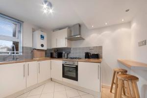 uma cozinha com armários brancos e um forno com placa de fogão em Stunning 1-bed Flat in London 20 mins from Central London em Londres