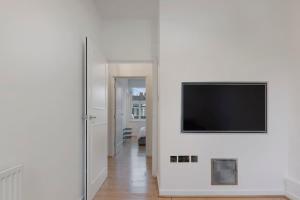 Stunning 1-bed Flat in London 20 mins from Central London في لندن: غرفة معيشة مع تلفزيون بشاشة مسطحة على جدار