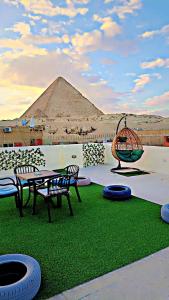 eine Terrasse mit einem Tisch, Stühlen und einer Pyramide in der Unterkunft Solima pyramids inn in Kairo