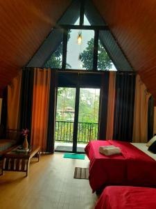 a bedroom with a red bed and a large window at Water Side Residence in Adams Peak