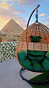 a bird cage with a chair in front of a pyramid at Solima pyramids inn in Cairo