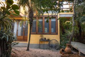 a house with a table in the middle of a garden at Pousada Colmeia - Praia de Santo André, Bahia in Santo André
