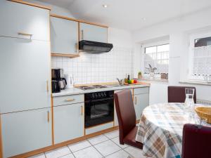 een keuken met witte kasten en een tafel met een tafelkleed bij Apartment Möwe by Interhome in Norddeich