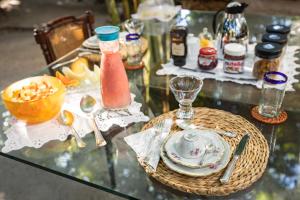 a glass table with a plate of food and a drink at Pousada Colmeia - Praia de Santo André, Bahia in Santo André