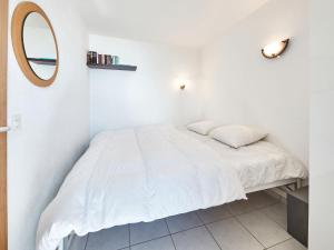 a white bedroom with a bed and a mirror at Apartment Zinal 204 by Interhome in Les Collons