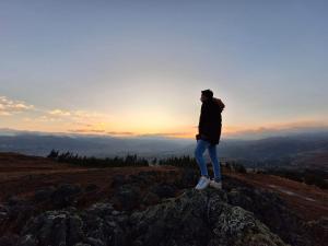 a person standing on top of a mountain at sunset at GLAMPING NAKAMA Cajamarca in Cajamarca