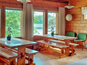 een kamer met houten tafels, stoelen en ramen bij Holiday Home Petäjälahti by Interhome in Petäjävesi