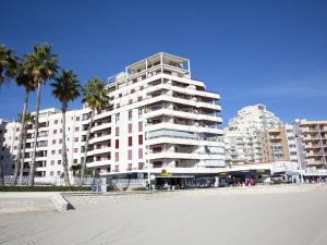 Un gran edificio blanco en la playa con palmeras. en Apartment Topacio IV-1 by Interhome, en Calpe