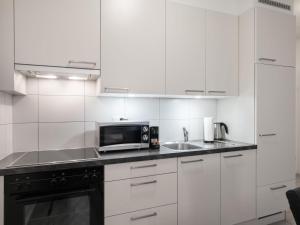 uma cozinha branca com um micro-ondas e um lavatório em Apartment Victoria View by Interhome em Interlaken