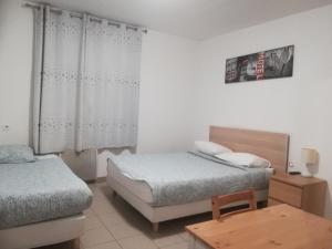 sypialnia z 2 łóżkami i drewnianym stołem w obiekcie Hôtel Vauban w mieście Livry-Gargan