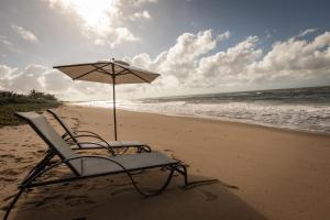a chair and an umbrella on the beach at Pousada Colmeia - Praia de Santo André, Bahia in Santo André